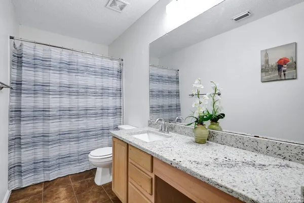 a bathroom with a granite countertop toilet sink and mirror