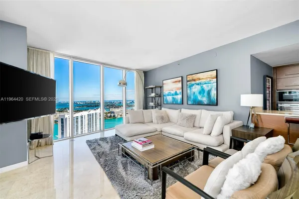 a living room with furniture a flat screen tv and a large window