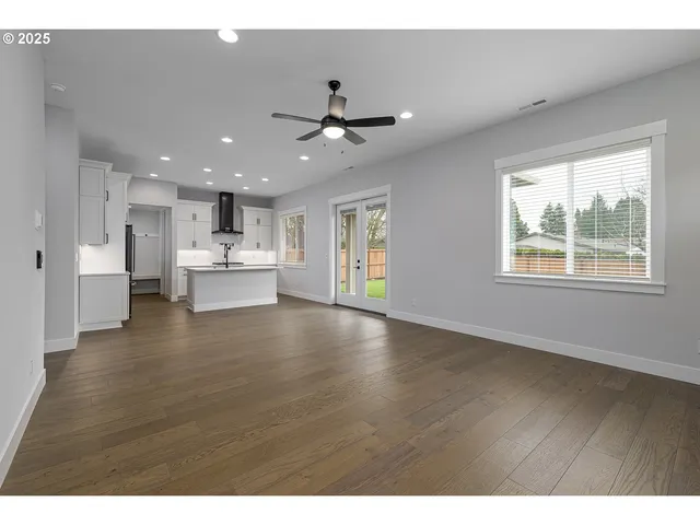 a view of an empty room with window and wooden floor
