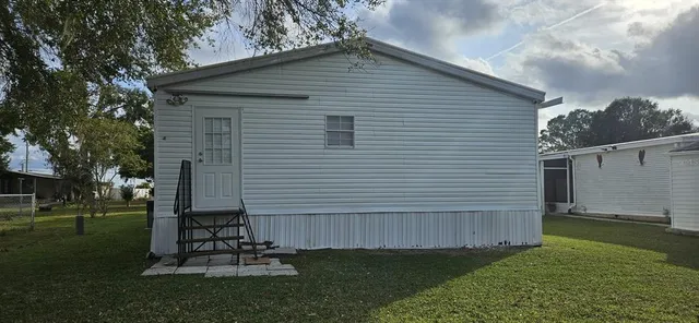 a view of a white house with a large window and a yard