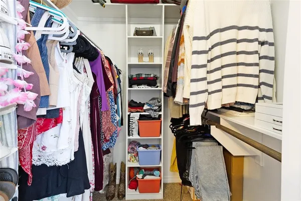 a view of walk in closet with clothes and shoes