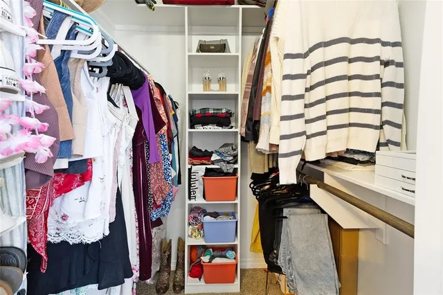 a view of walk in closet with clothes and shoes