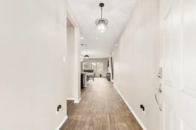 a view of a hallway with wooden floor and a bathroom