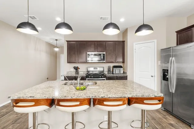 a kitchen with granite countertop kitchen island stainless steel appliances a dining table and chairs