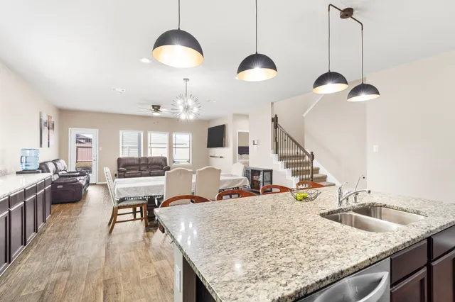 a kitchen with granite countertop kitchen island stainless steel appliances a sink stove and refrigerator