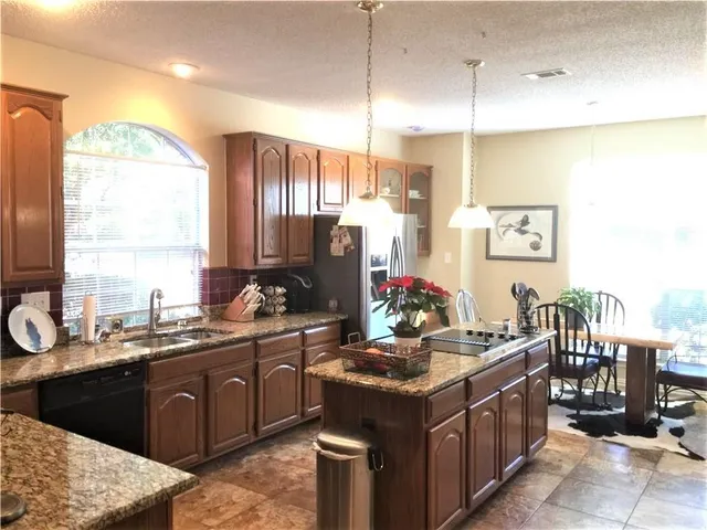 a kitchen with stainless steel appliances kitchen island granite countertop a refrigerator a sink and a stove