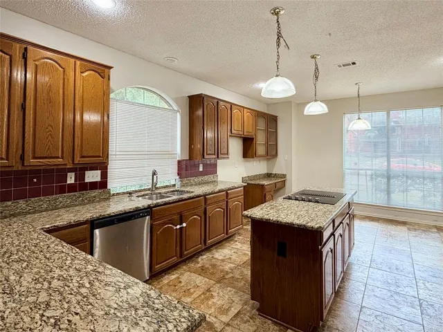 a kitchen with stainless steel appliances granite countertop a sink a stove top oven a counter space and cabinets