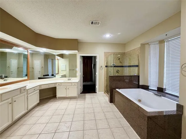 a large white bathroom with a granite countertop double vanity sink a mirror and a bathtub