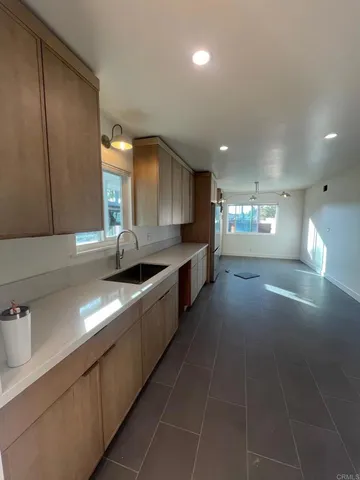 a large kitchen with granite countertop a sink a counter space and cabinets