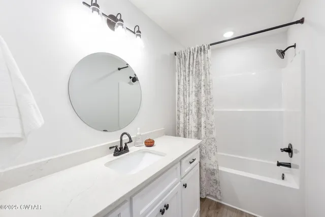 a bathroom with a sink a mirror a bathtub and shower