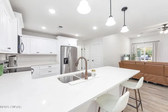 a kitchen with stainless steel appliances kitchen island granite countertop a table chairs and a refrigerator