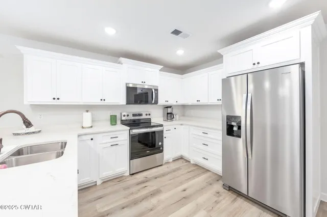 a kitchen with white cabinets and stainless steel appliances