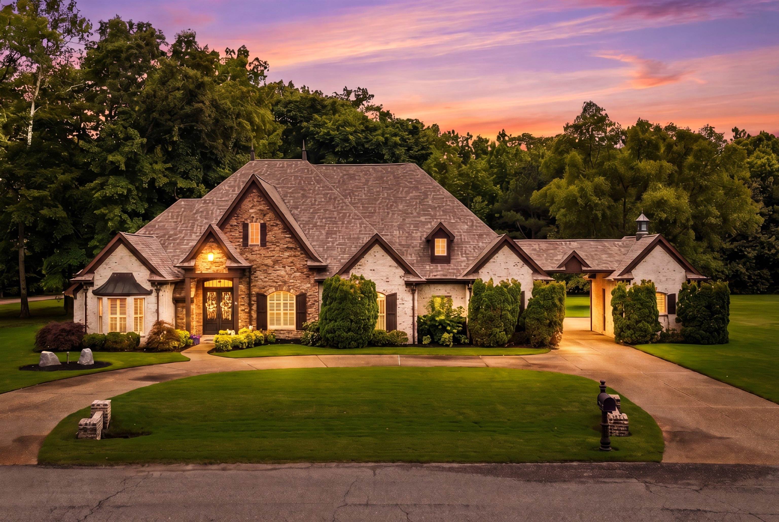 Stone and brick facade residence featuring a circular driveway, prominent gables, and a porte-cochere leading to an enclosed motor court