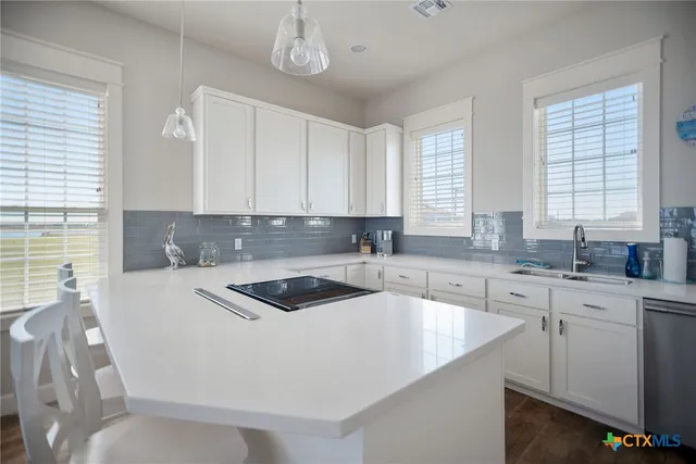 a kitchen with granite countertop a sink stainless steel appliances white cabinets and a window