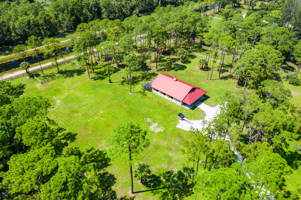1835 Stallion Drive, Unit STALLS Loxahatchee, FL 33470 - Photo 15 of 35 a backyard of a house with lots of green space and bench