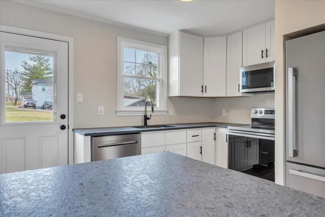 a kitchen with granite countertop white cabinets and stainless steel appliances
