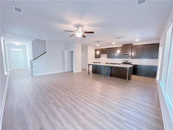 a large kitchen with stainless steel appliances granite countertop a oven and a large countertops with wooden floor