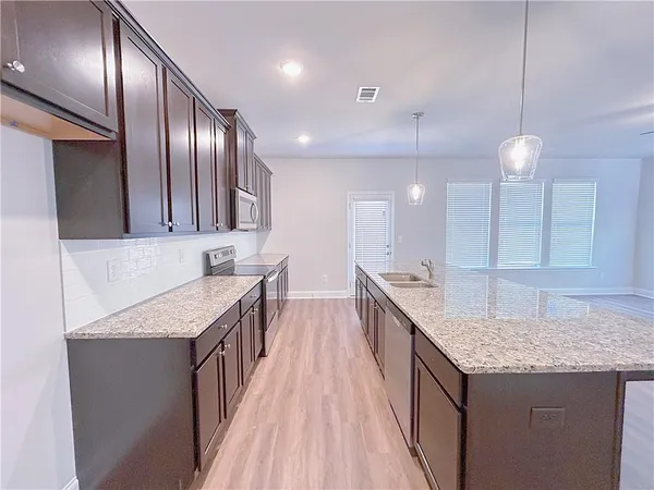 a kitchen with granite countertop kitchen island a sink appliances and a counter top space