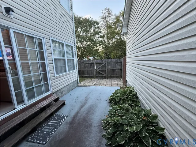 a view of a pathway with a white house with wooden floor and fence next to a yard