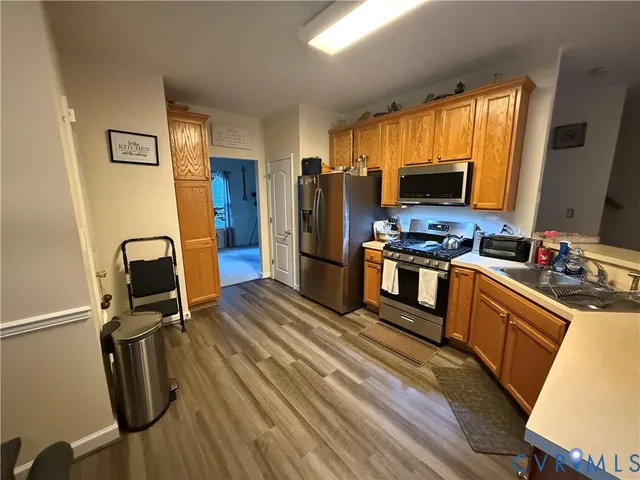 a kitchen with stainless steel appliances granite countertop a stove top oven a refrigerator a sink dishwasher and a stove with wooden floor