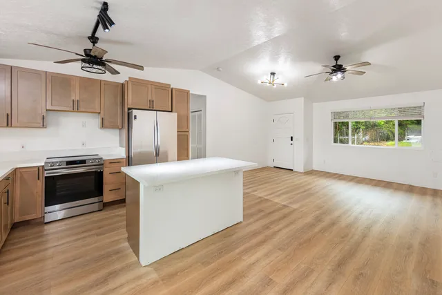 a kitchen with stainless steel appliances a stove top oven a refrigerator cabinets and wooden floor