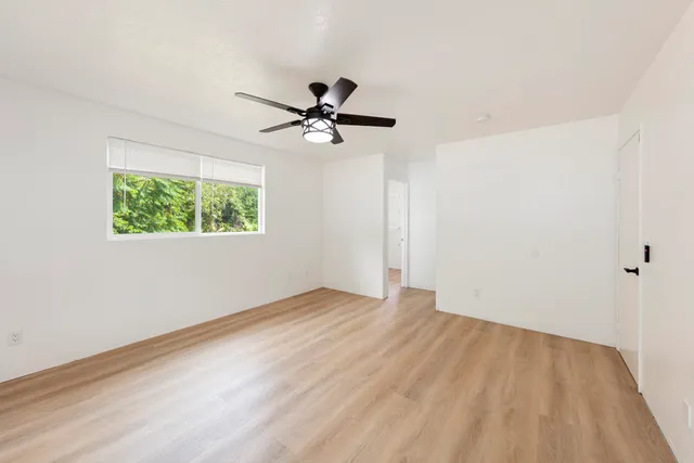 a view of a big room with wooden floor and a chandelier fan