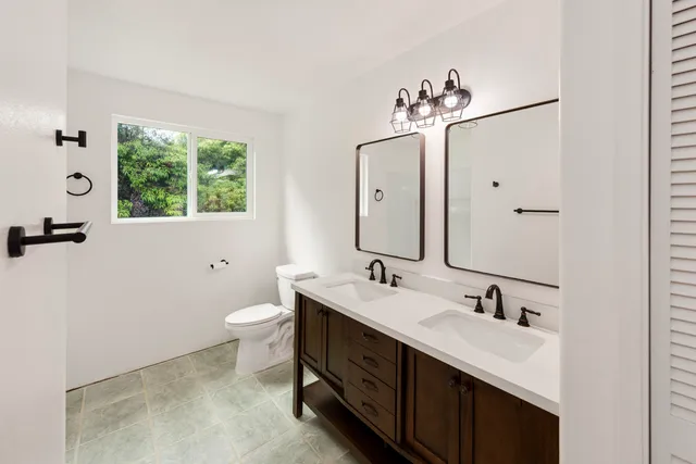 a spacious bathroom with a double vanity sink a mirror and a toilet