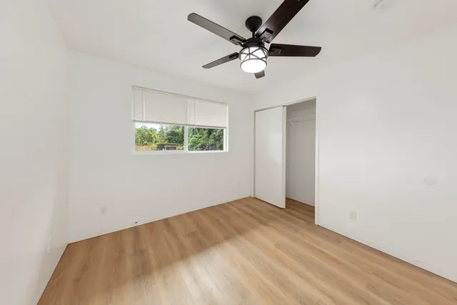 an empty room with a window and a fan