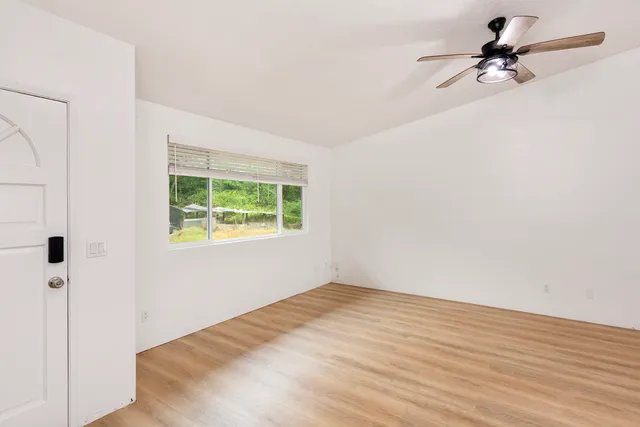 an empty room with a window and a ceiling fan