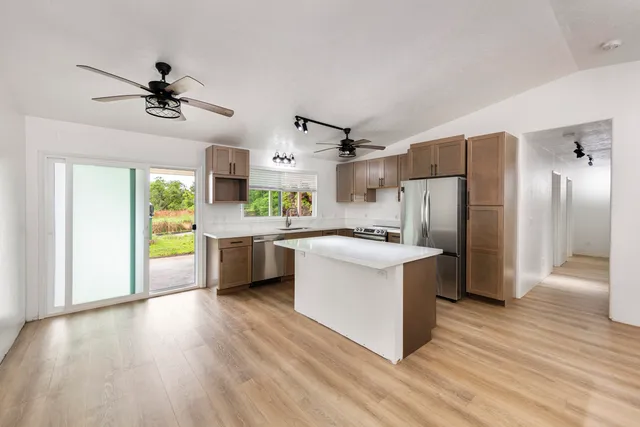 a kitchen with stainless steel appliances a refrigerator a sink dishwasher a stove and a dining table with wooden floor
