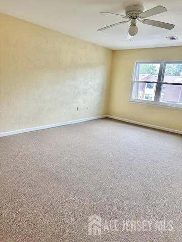 an empty room with a ceiling fan and a window