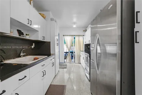 a large white kitchen with a sink and refrigerator