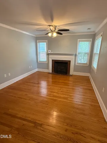 an empty room with wooden floor fireplace and windows