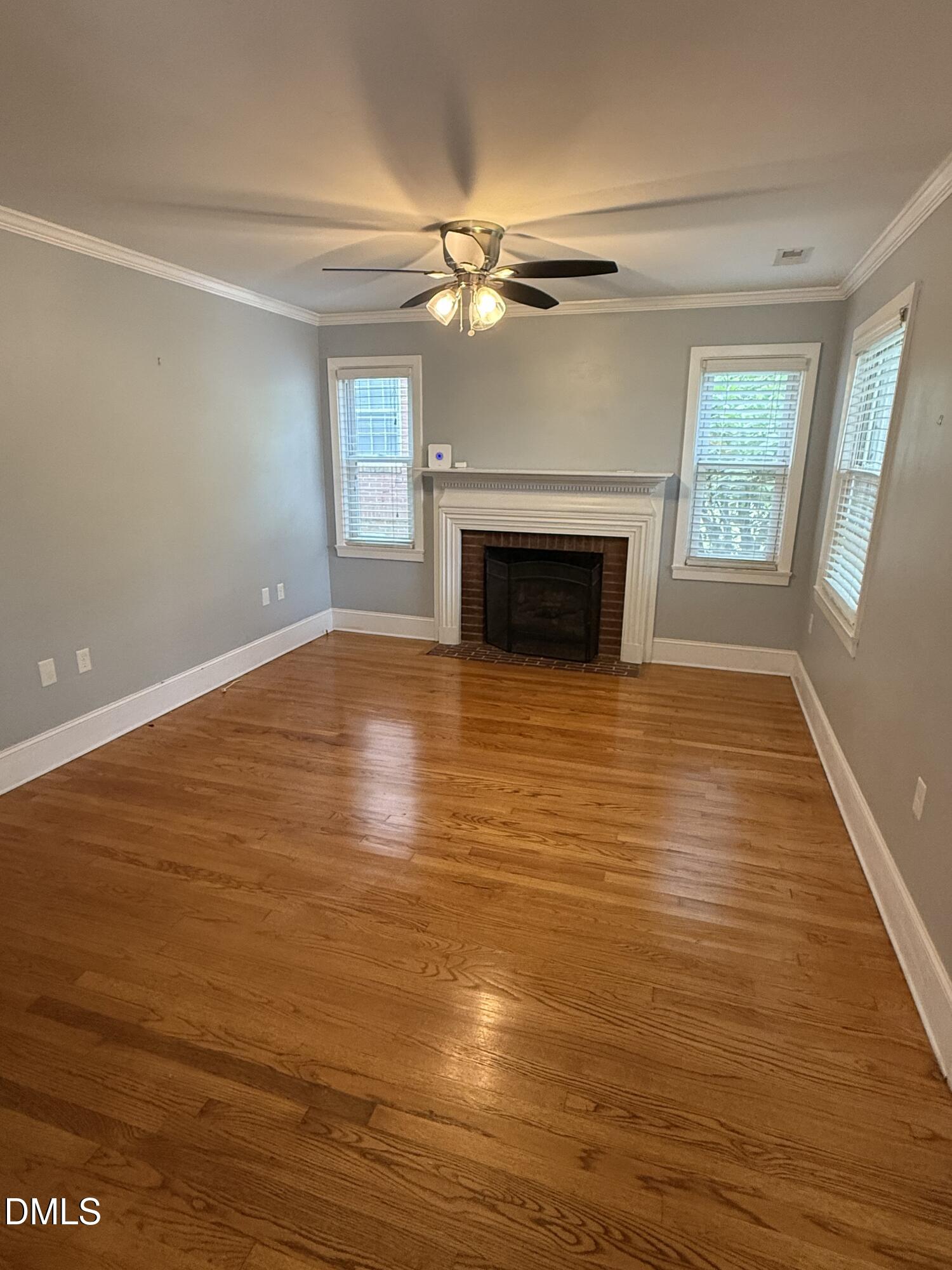 403 Brooks Avenue Raleigh, NC 27607 - Photo 3 of 9 an empty room with wooden floor fireplace and windows