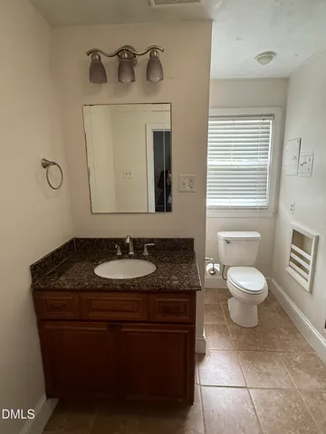 a bathroom with a granite countertop sink a toilet and a mirror