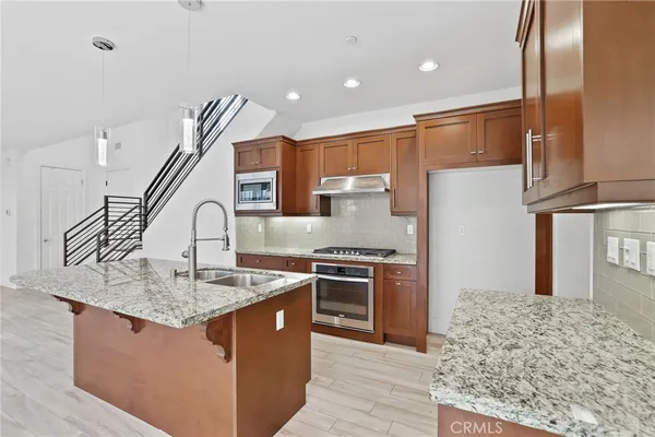 a kitchen with stainless steel appliances granite countertop a stove a sink and a refrigerator