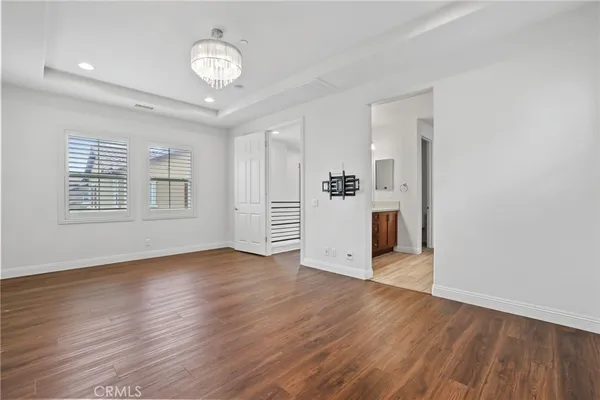 an empty room with wooden floor cabinet and windows