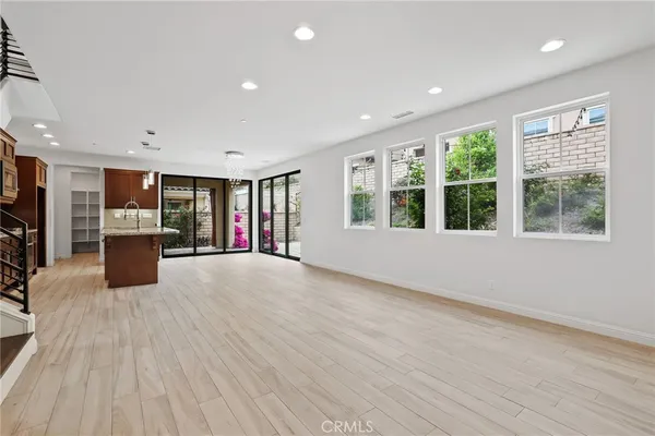 a view of an empty room with a window and kitchen