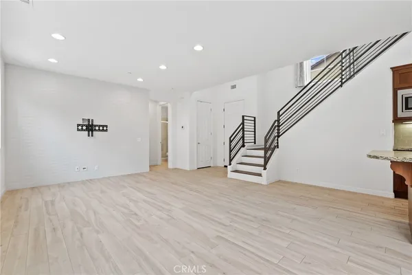 a view of an empty room with wooden floor and stairs