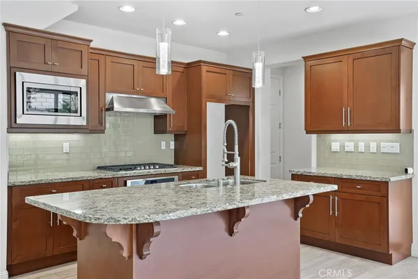 a kitchen with stainless steel appliances granite countertop a sink refrigerator and cabinets
