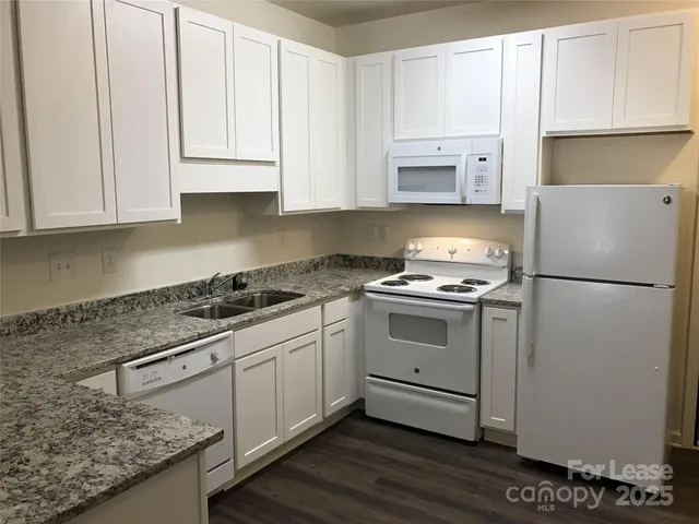 a kitchen with granite countertop white cabinets and white appliances