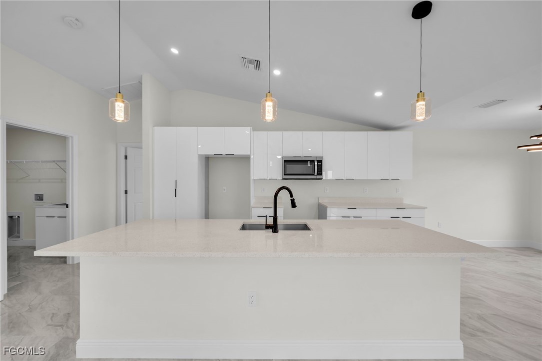 4106 35th Street Southwest Lehigh Acres, FL 33976 - Photo 9 of 38 a kitchen with kitchen island a sink stainless steel appliances and cabinets