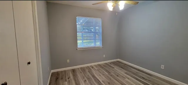 a view of an empty room with wooden floor and a window