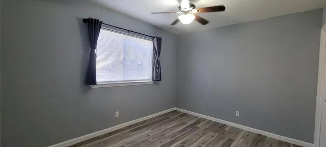 an empty room with windows and fan