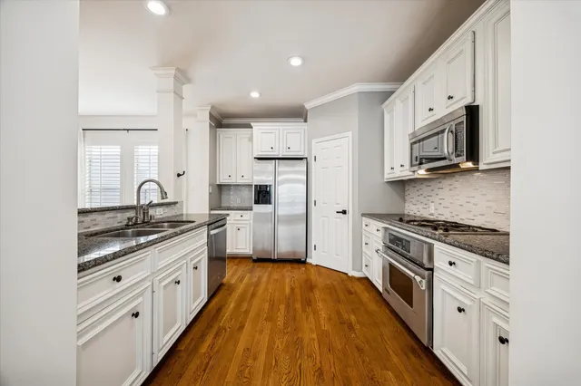 a kitchen with stainless steel appliances granite countertop a stove a sink and a refrigerator