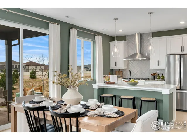 a open kitchen with stainless steel appliances kitchen island granite countertop a dining table chairs sink and cabinets