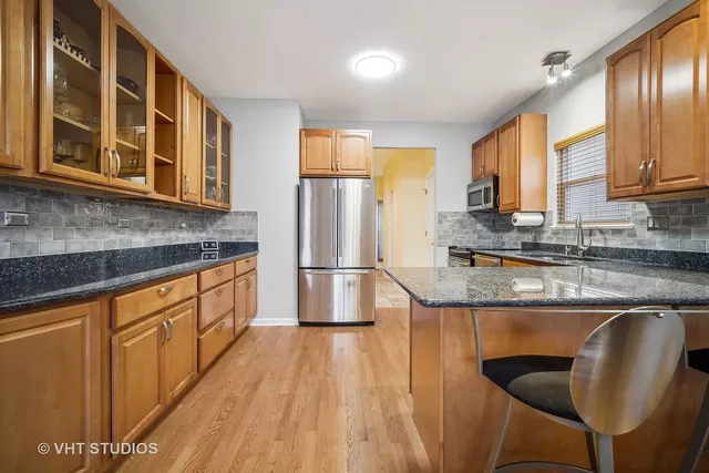 a kitchen with stainless steel appliances granite countertop a stove a sink dishwasher a refrigerator and cabinets with wooden floor