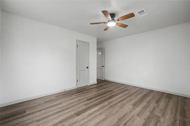 an empty room with wooden floor and ceiling fan