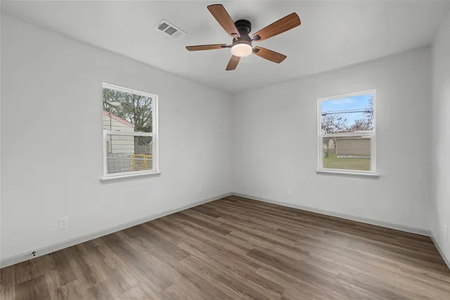 a view of an empty room with a window and a ceiling fan