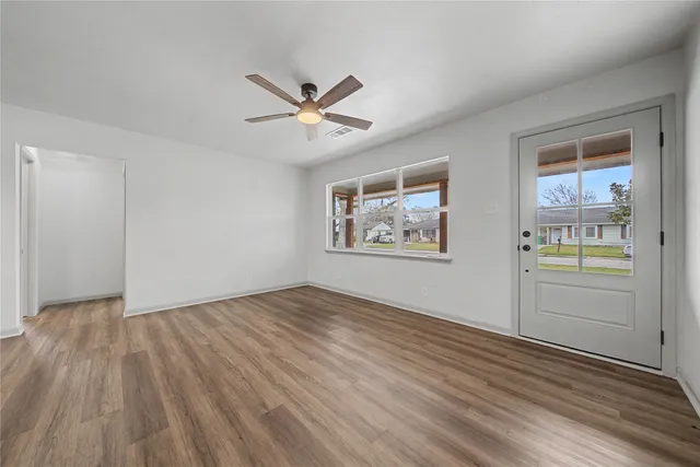 a view of empty room with wooden floor and fan